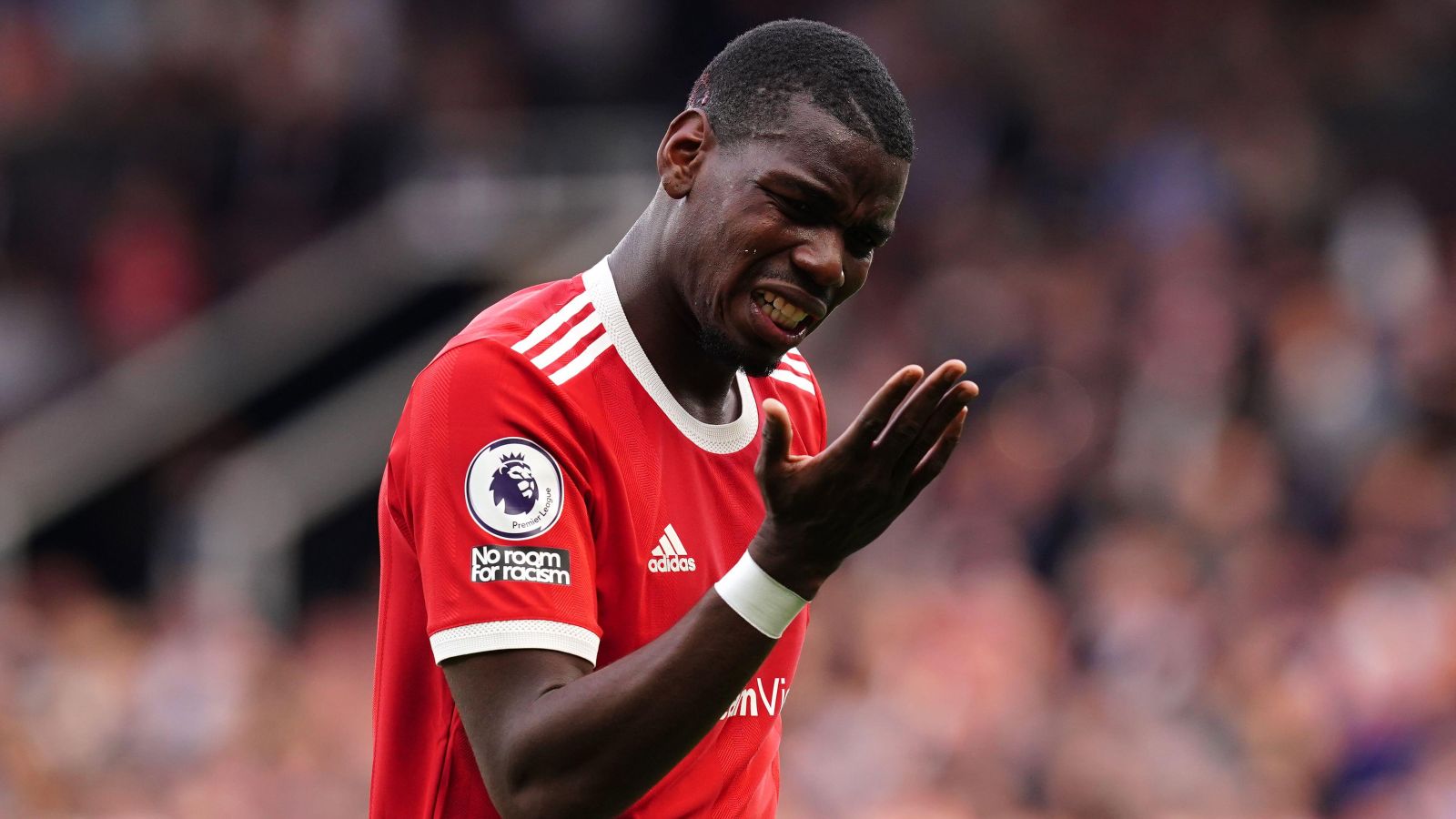 Man Utd midfielder Paul Pogba grimaces and looks at his hand