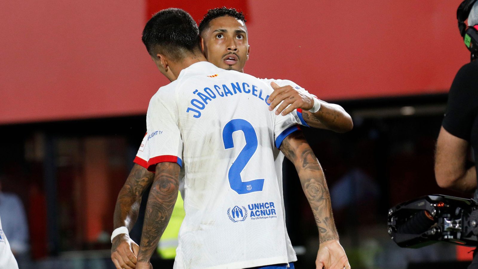 Barcelona winger Raphinha hugs Joao Cancelo during a match.
