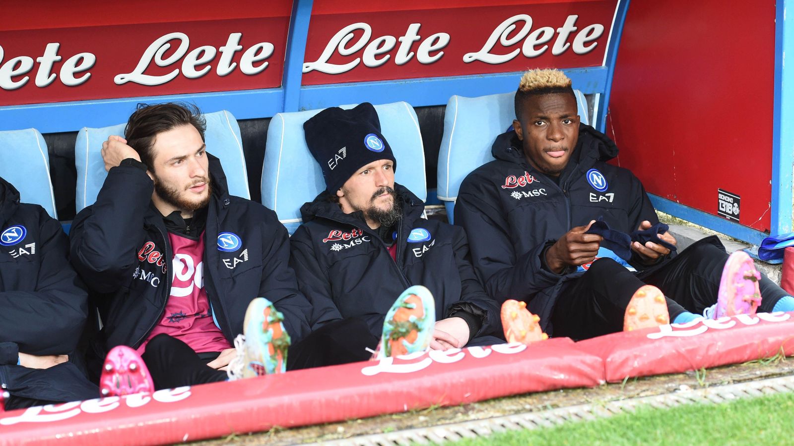 Victor Osimhen and Khvicha Kvaratskhelia sit on the bench during a match.