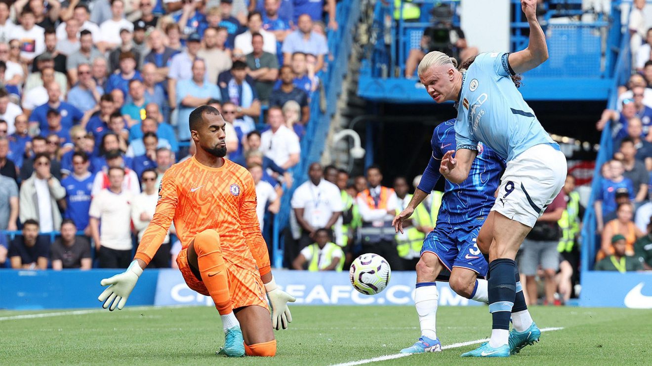 Manchester City's Erling Haaland lifts the ball past Chelsea's Robert Sanchez, who is kneeling down to try and block it at close range
