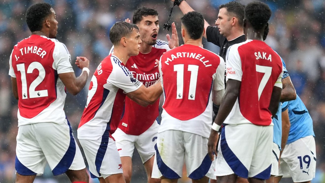 Arsenal surround Michael Oliver after Leandro Trossard's red card.