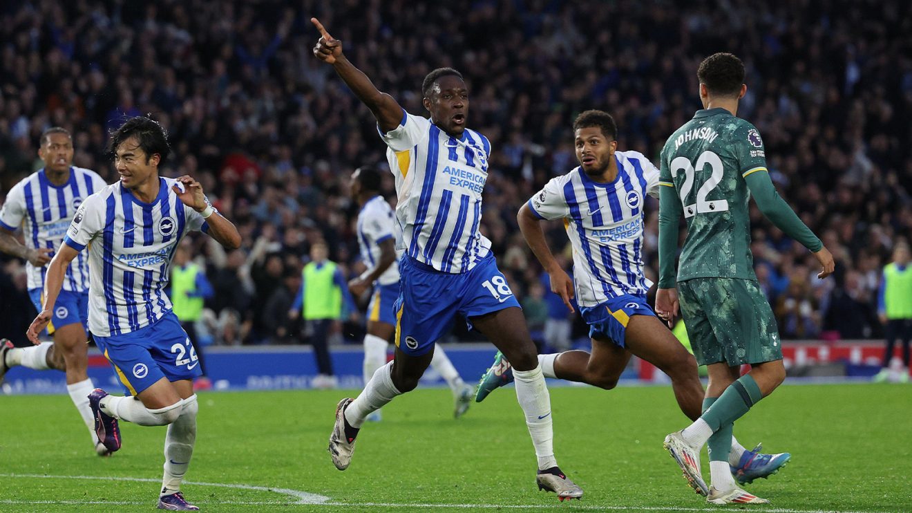 Danny Welbeck is surrounded by joyous teammates as Tottenham's Brennan Johnson walks away, dejected