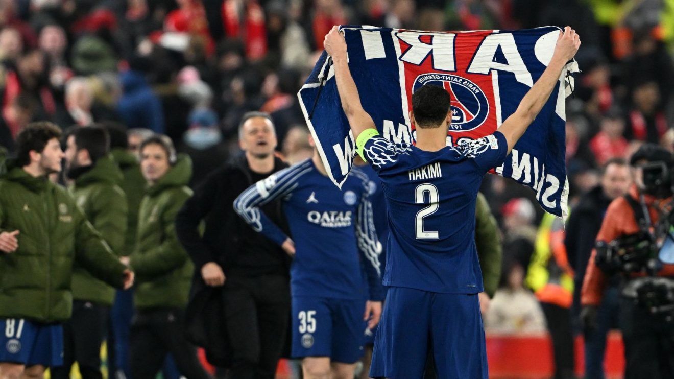 Achraf Hakimi holds up a Paris Saint-Germain flag after the Champions League win over Liverpool at Anfield