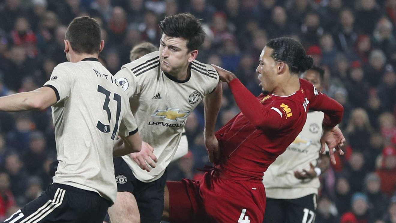 Manchester United defender Harry Maguire is challenged by Liverpool player Virgil van Dijk