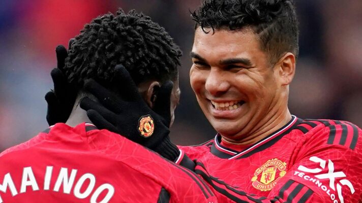Kobbie Mainoo is embraced by Manchester United teammate Casemiro