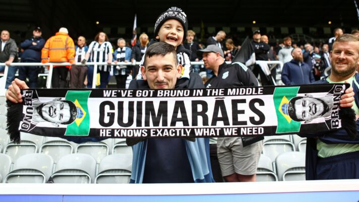 A Newcastle fan holds up a Bruno Guimarães scarf