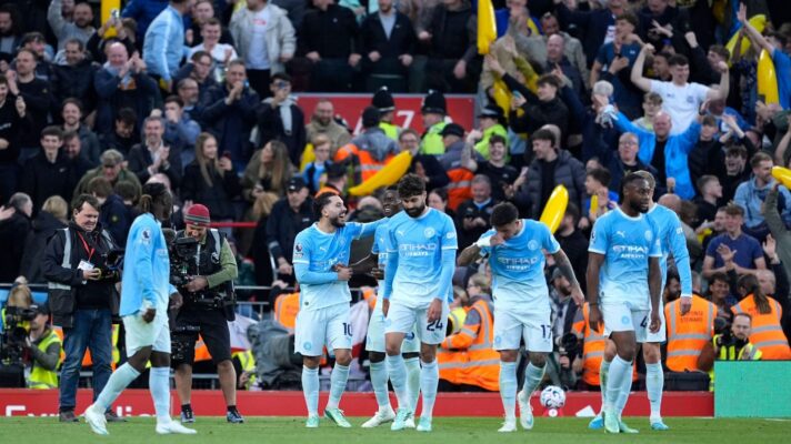 Manchester City players celebrate in front of inflatable bananas at Anfield.
